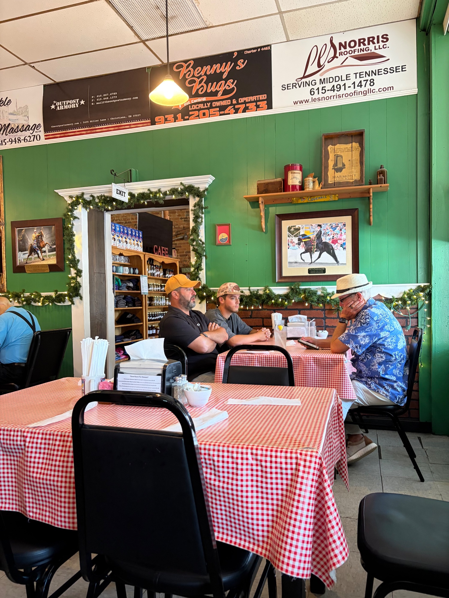 Cafe interior with green walls, red checked tables and customers in hats at lunch