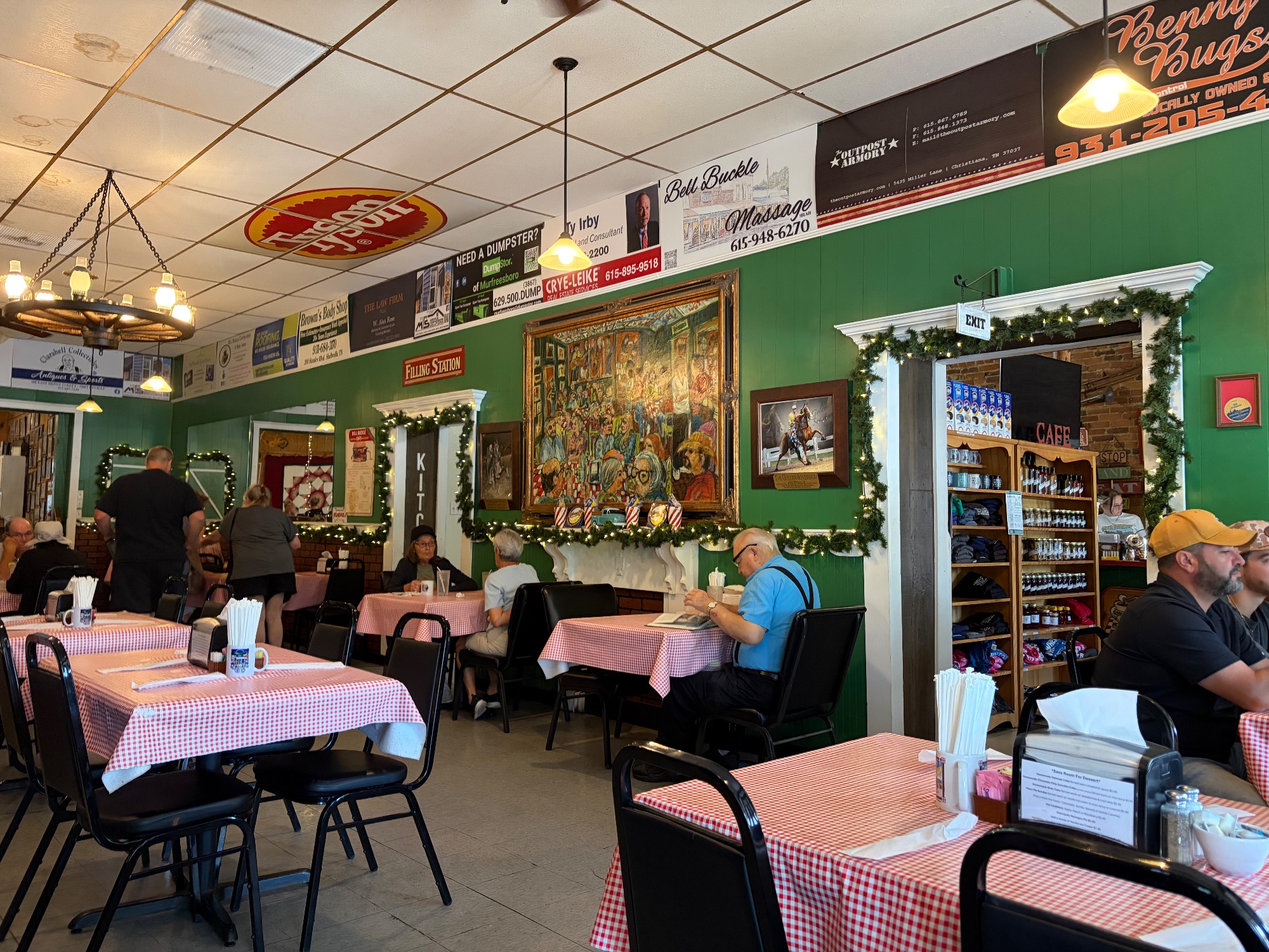 Wide view of the cafe dining room with green walls, checked tables and diners